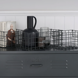 A set of 3 slate grey baskets containing a book a vase and cups, sat on a on a grey metal Lambeth locker.